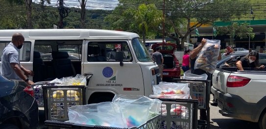 foto de uma kombi do TRE-RJ, com uma fila de carrinhos de compra ao lado